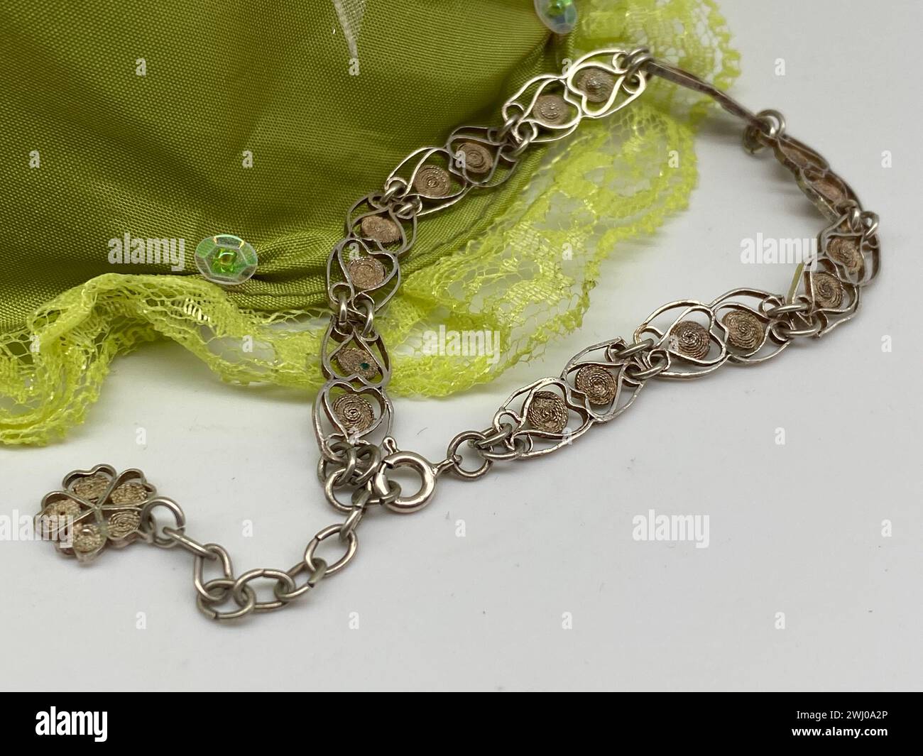 Silver chain with brass charms and glasses on green lace Stock Photo