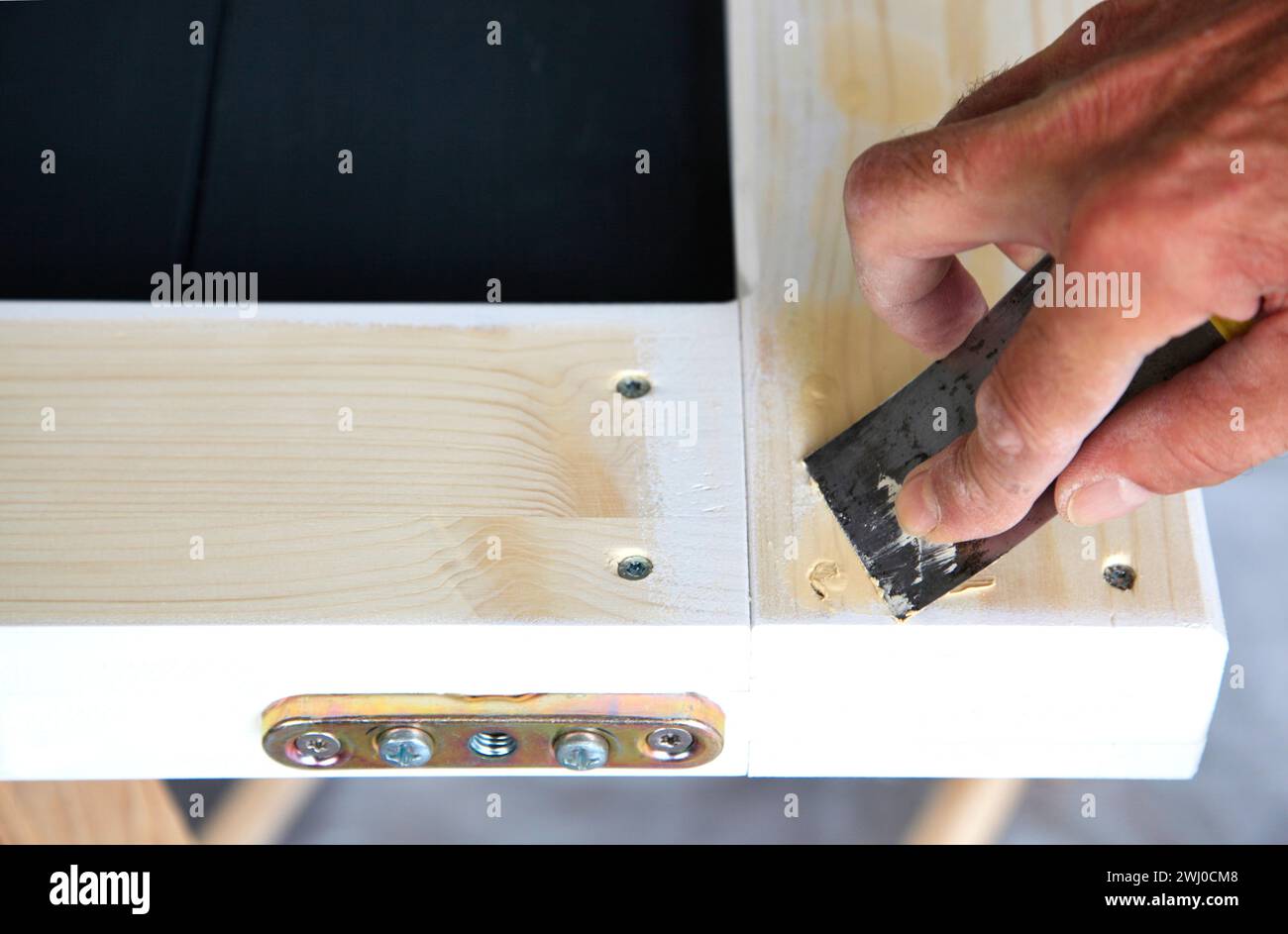 Woodwork. Closeup Putty knife in man's hand. DIY worker applying