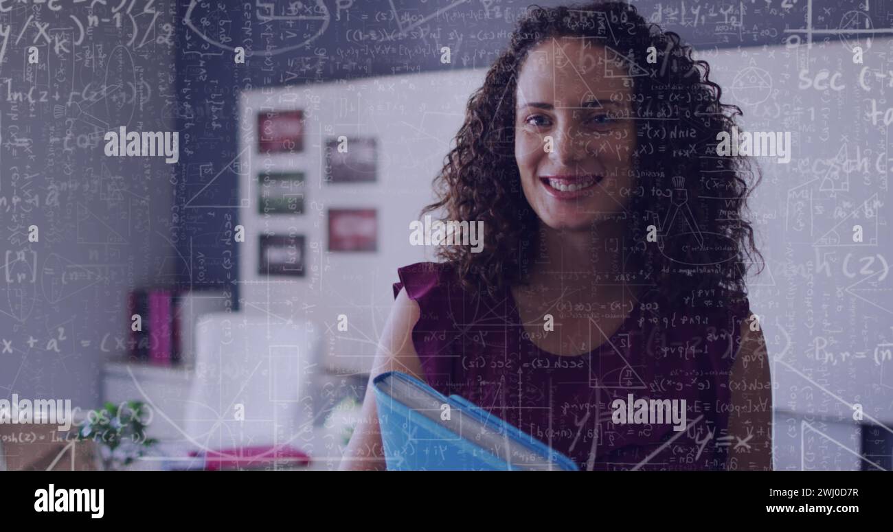 Image of maths calculations over happy biracial female teacher in classroom Stock Photo