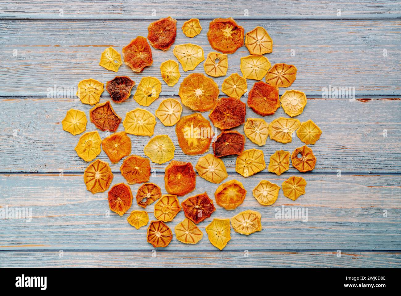 Fruit chips are laid out in a circle on blue worn horizontal wooden planks Stock Photo