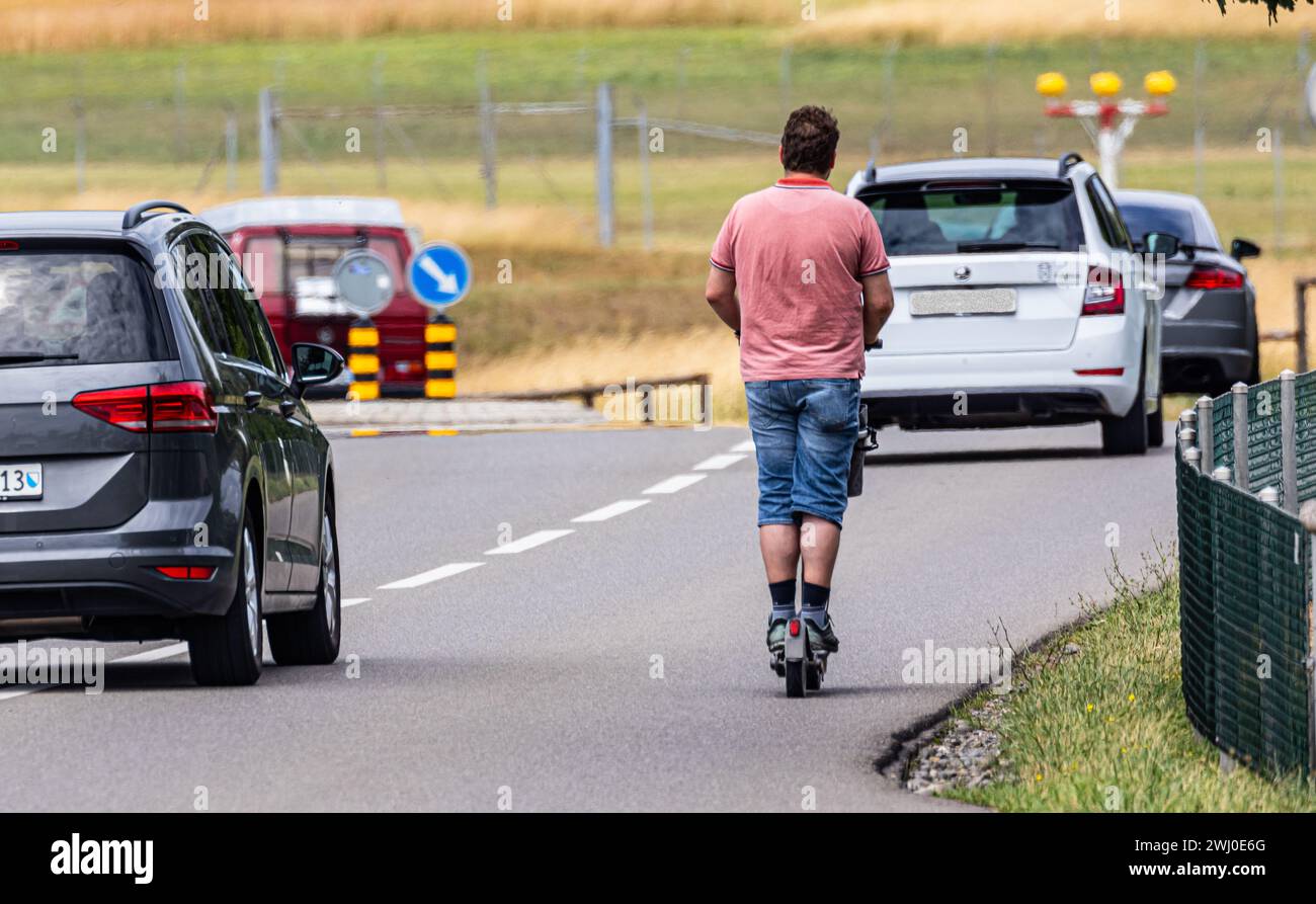 Ein Mann fährt mit seinem auf einer dichtbefahrenenen Strasse ausserorts