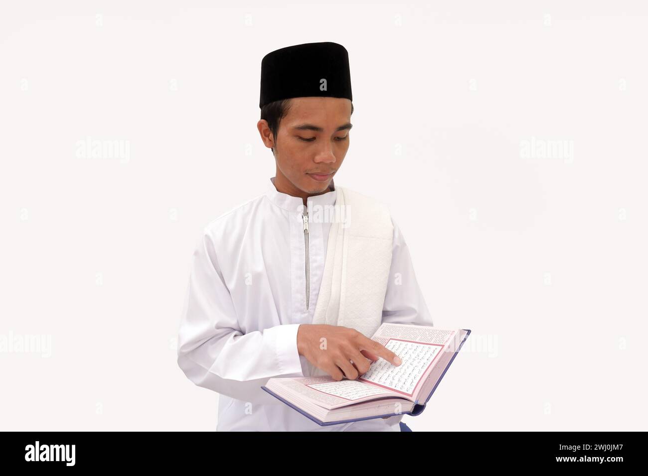 Palembang, Indonesia, February 10, 2024: Asian Muslim Man reading the Al Quran in his Hand with arabic text meaning of the Al Quran. Stock Photo