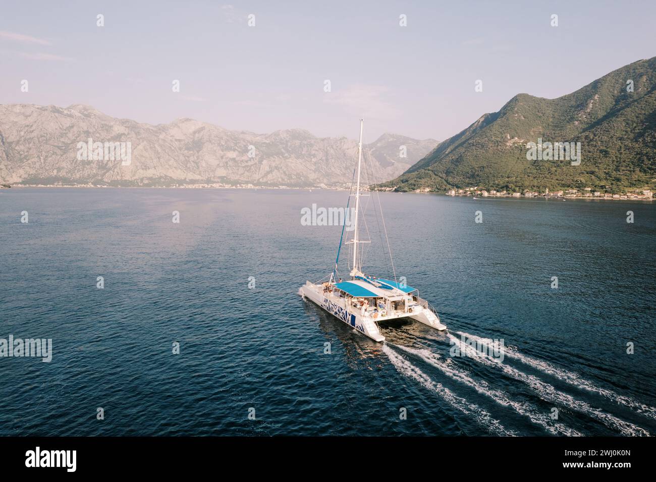 Large passenger sailing catamaran floats on the sea along the mountains. Drone Stock Photo