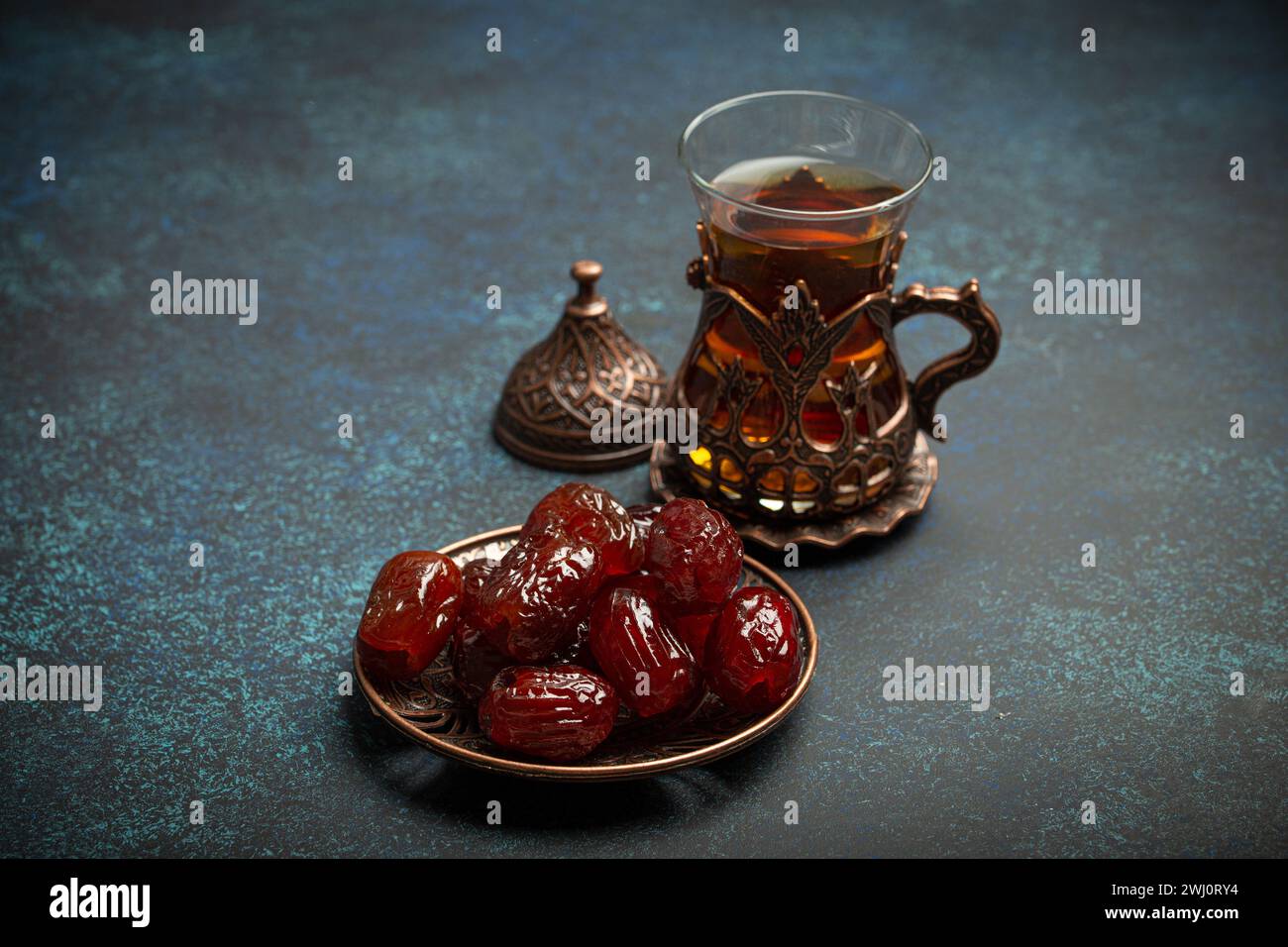 Breaking fasting with dried dates during Ramadan Kareem, Iftar meal with dates and Arab tea in traditional glass, angle view on Stock Photo