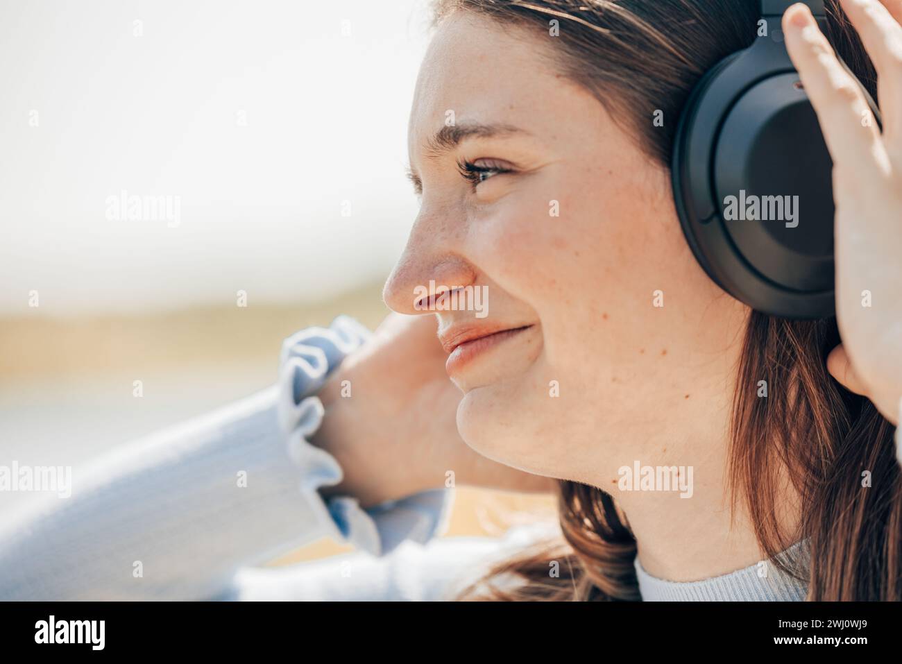 Beach Beats: Sunlit Tourist Enjoys Music by the Sea Stock Photo