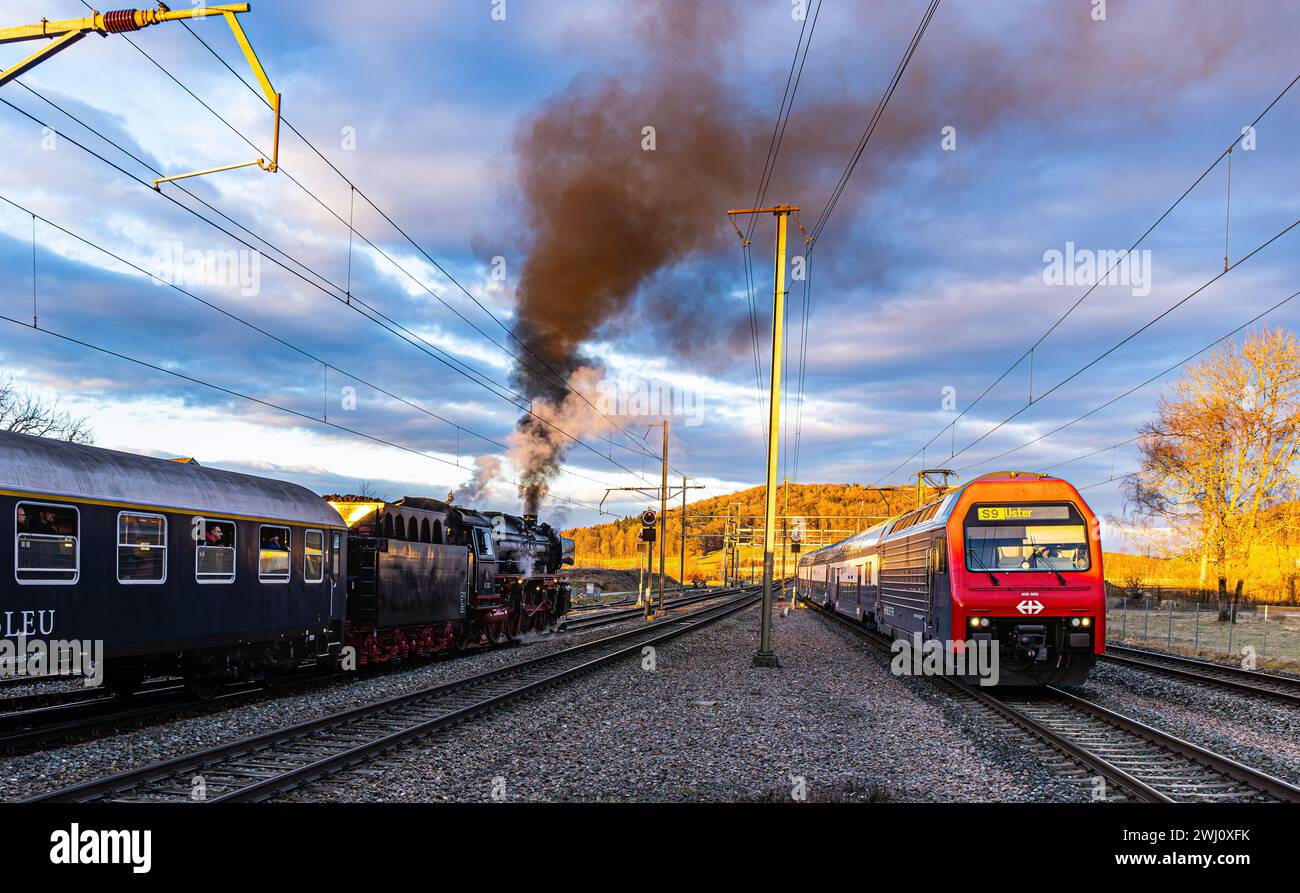 Alt trifft auf modern. Die S9, welche seit den 1990er in der Zürcher S-Bahn fährt, trifft auf die wartende Dampflokomotive der Baureihe 01 mit Baujahr Stock Photo