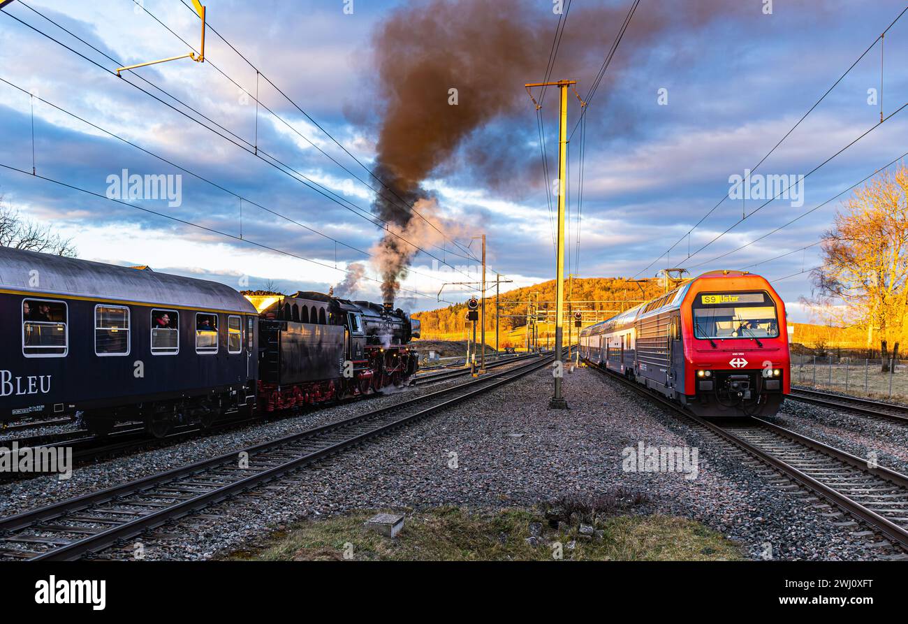 Alt trifft auf modern. Die S9, welche seit den 1990er in der Zürcher S-Bahn fährt, trifft auf die wartende Dampflokomotive der Baureihe 01 mit Baujahr Stock Photo