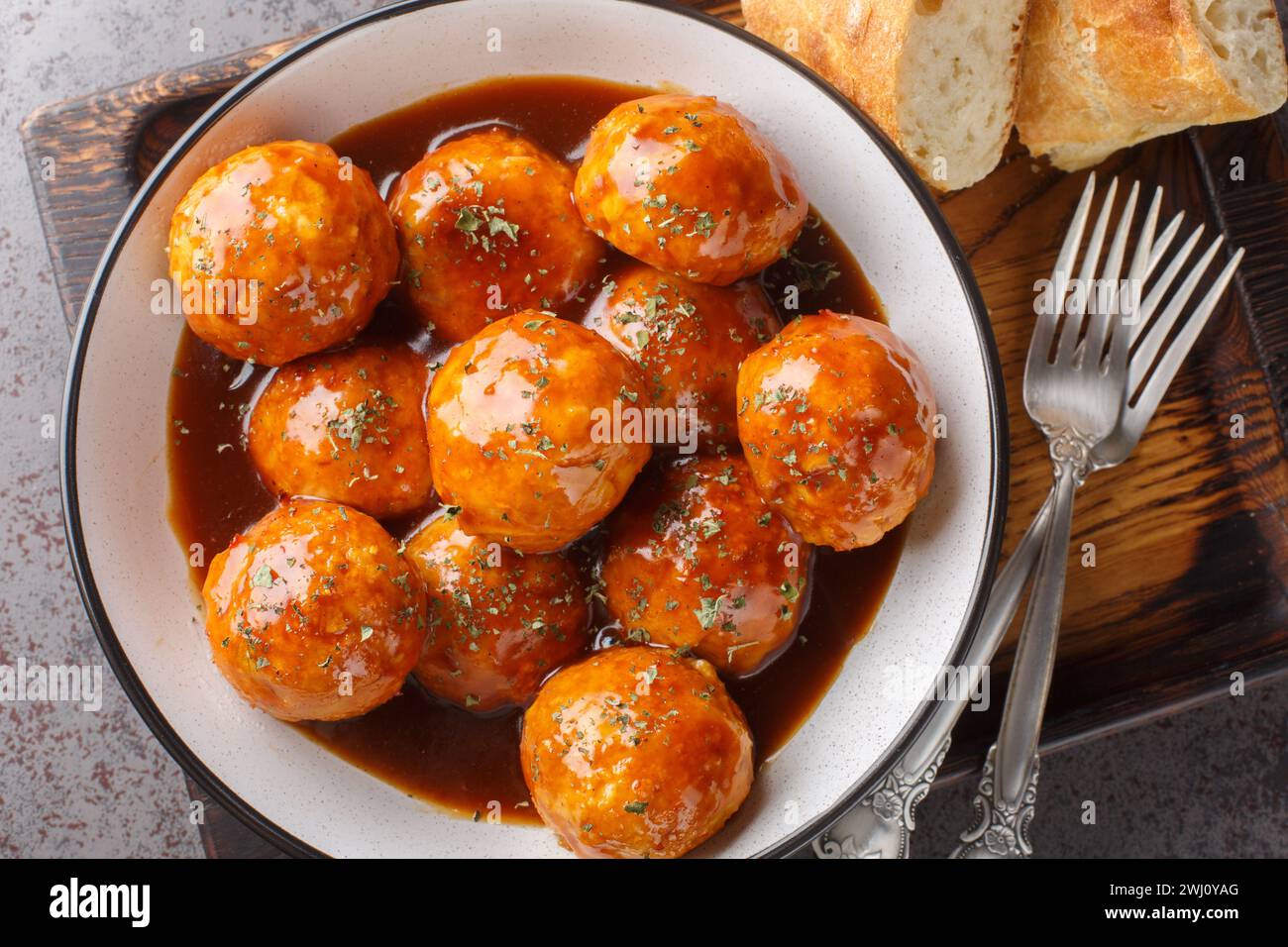 Baked meatballs are coated in a sweet and spicy honey chipotle sauce closeup on the bowl on the table. Horizontal top view from above Stock Photo