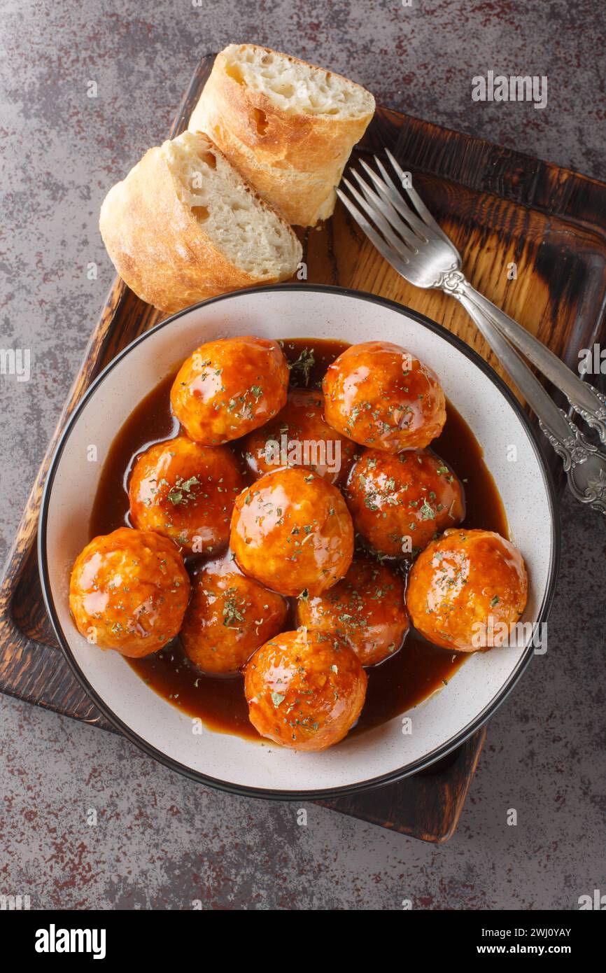 Smoky, spicy and sweet chicken meatballs tossed in our Honey Chipotle BBQ sauce closeup on the bowl on the table. Vertical top view from above Stock Photo