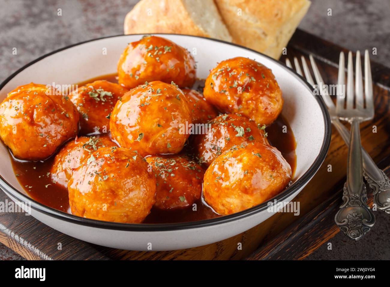Baked meatballs are coated in a sweet and spicy honey chipotle sauce closeup on the bowl on the table. Horizontal Stock Photo