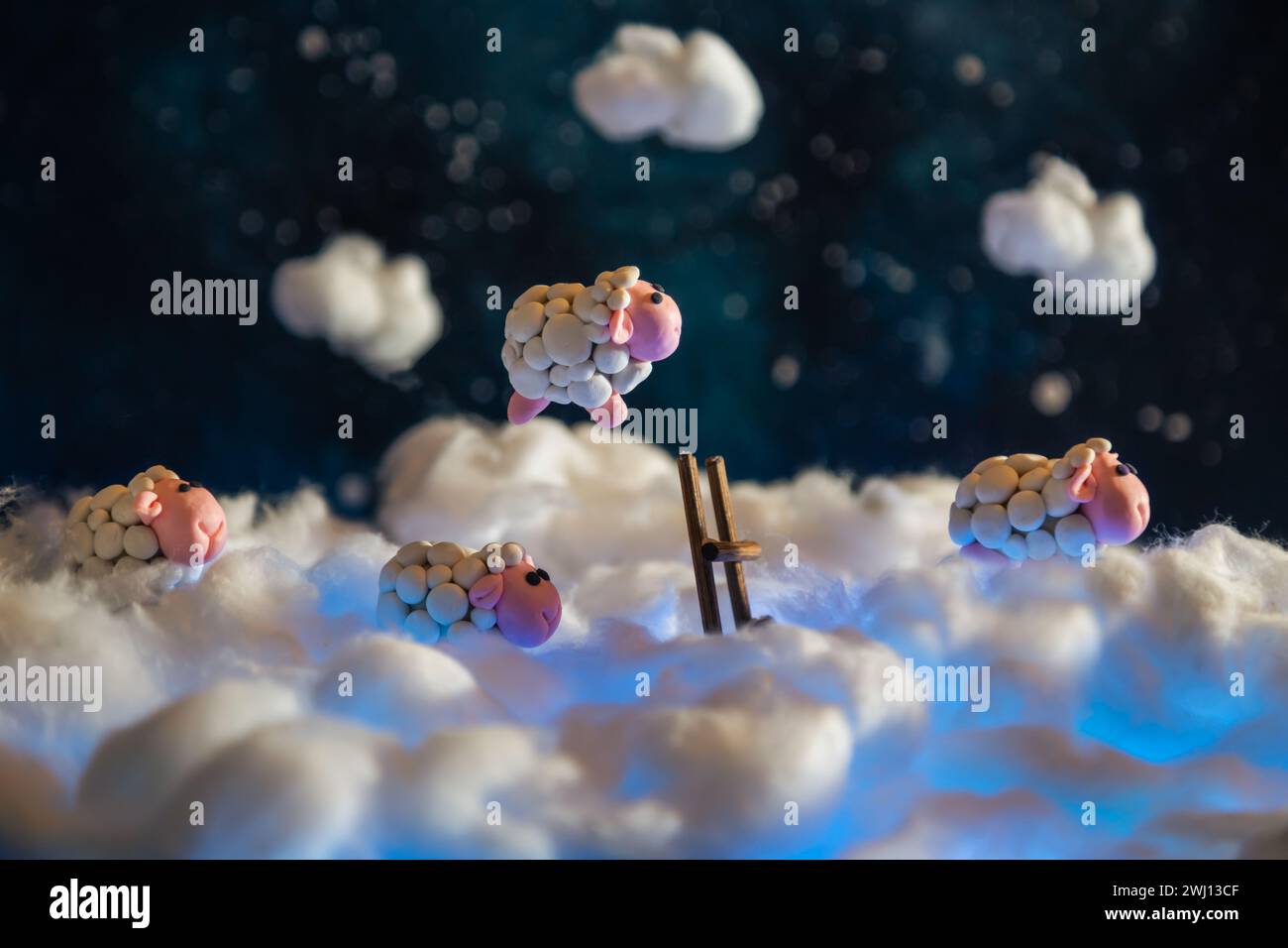 Cute plasticine sheep jumping over a fence in the clouds. Count sheep for insomnia. Night sky with stars. Stock Photo