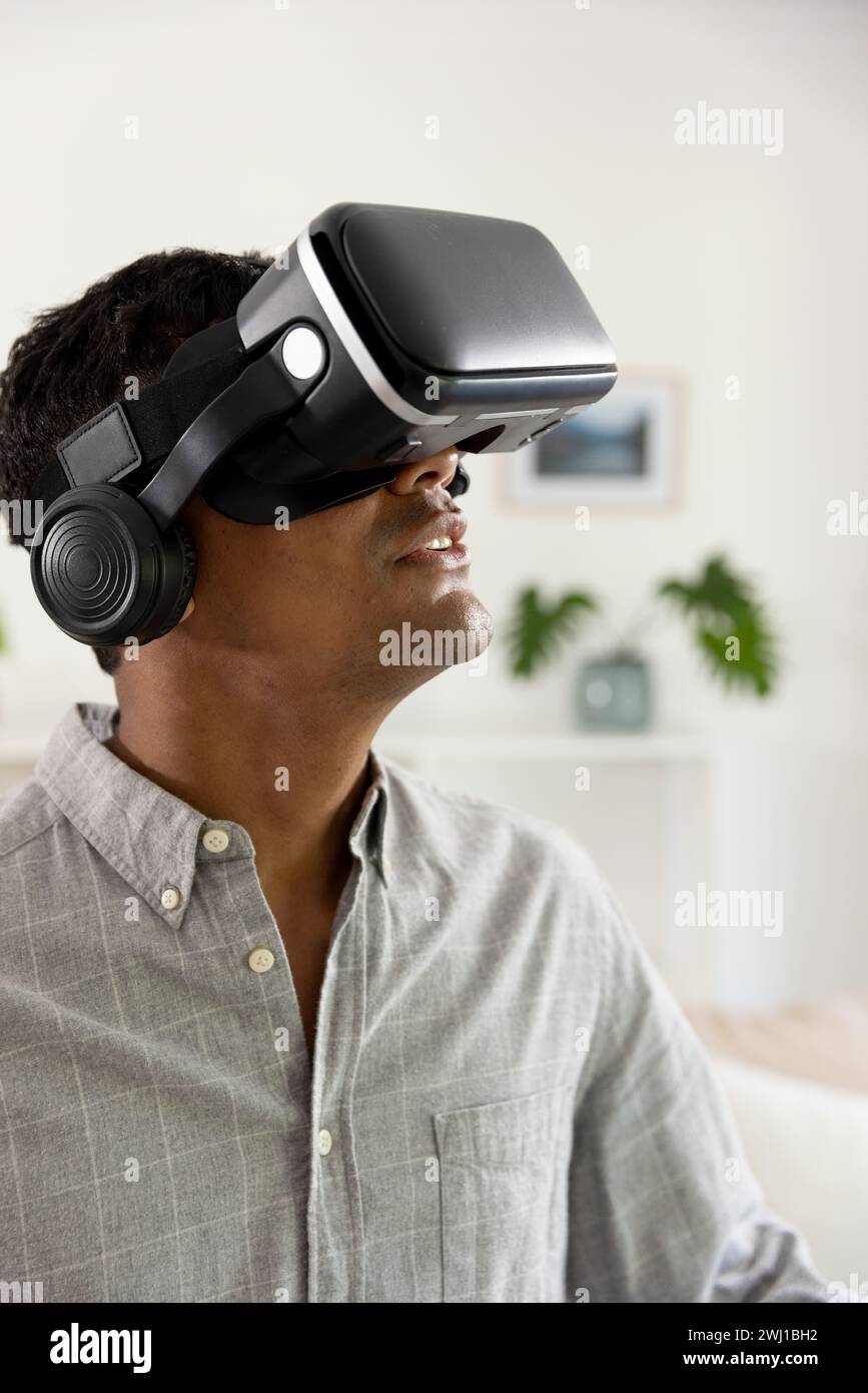 Happy biracial man using vr headset at home Stock Photo