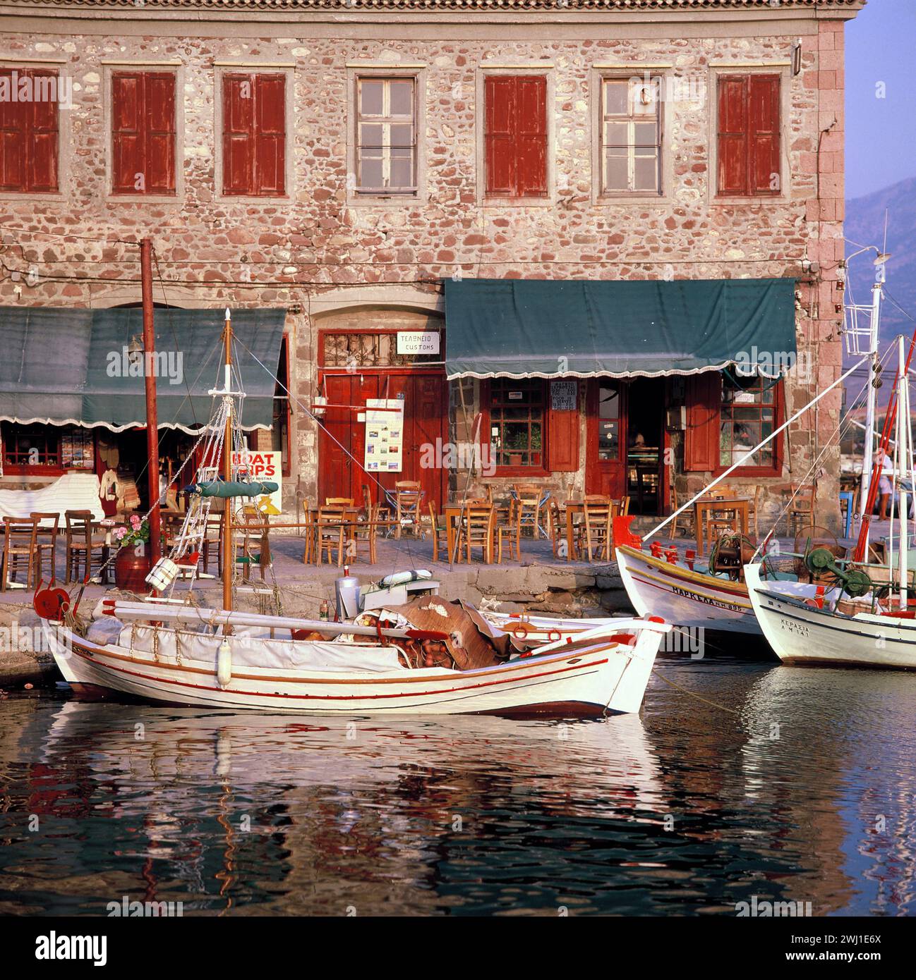 Greece. Lesbos Island. Molyvos. Waterfront café & moored boats. Stock Photo