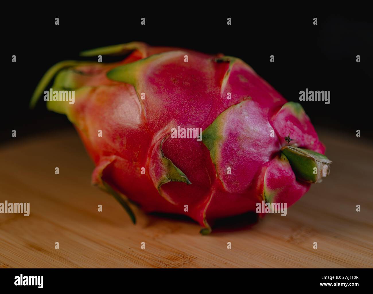 A dragonfruit on wooden table with dark backdrop Stock Photo
