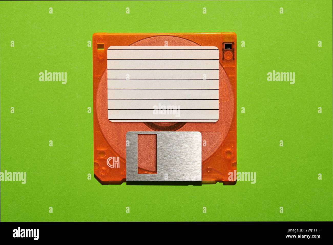 Top view of blank paper with lines stuck on brown floppy disk on green background Stock Photo