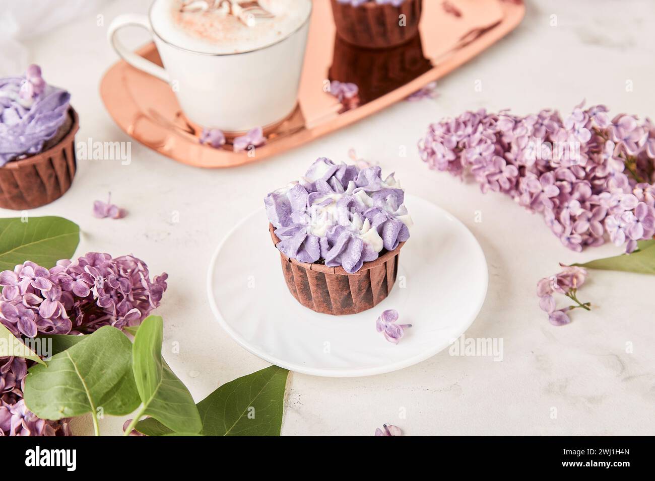Aesthetics close up purple floral cupcakes using trend Dreamy Escapism. Desserts and flowers background. Stock Photo