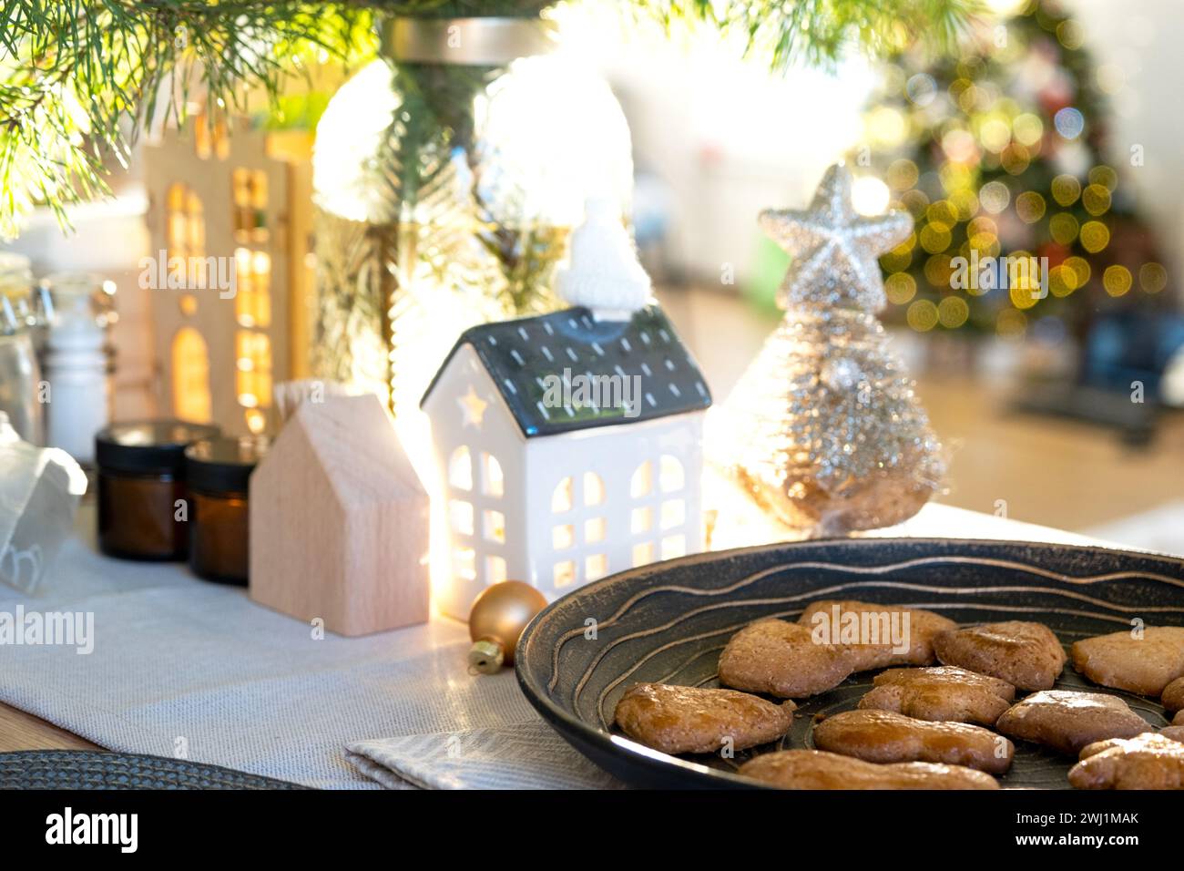 Festive Christmas decor in table, homemade cakes for breakfast, bakery cookies. Cozy home, christmas tree with fairy lights garl Stock Photo