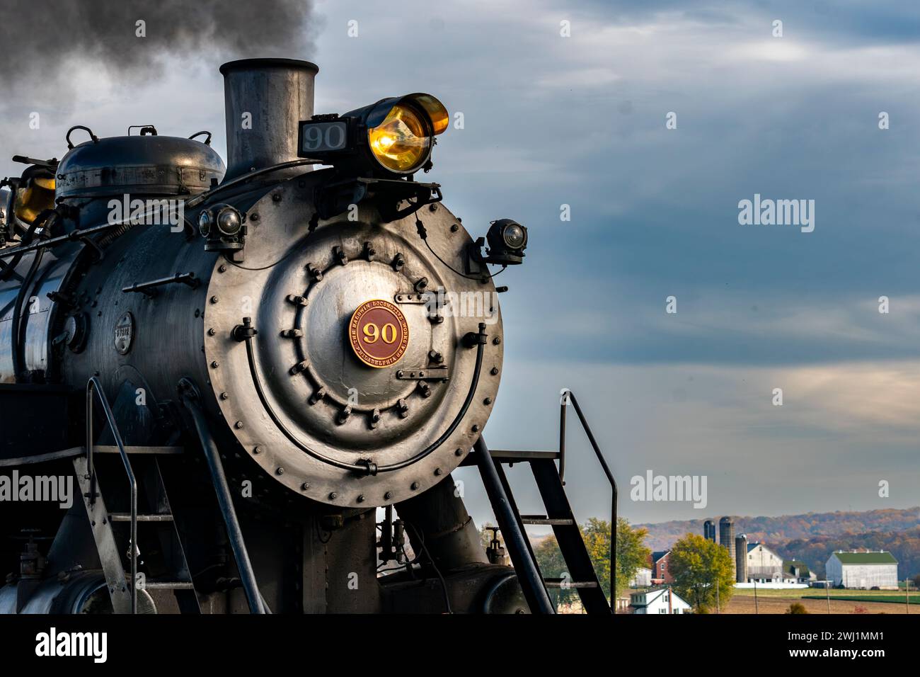 Close Up View of the Front of an Antique Steam Locomotive Blowing Smoke Stock Photo