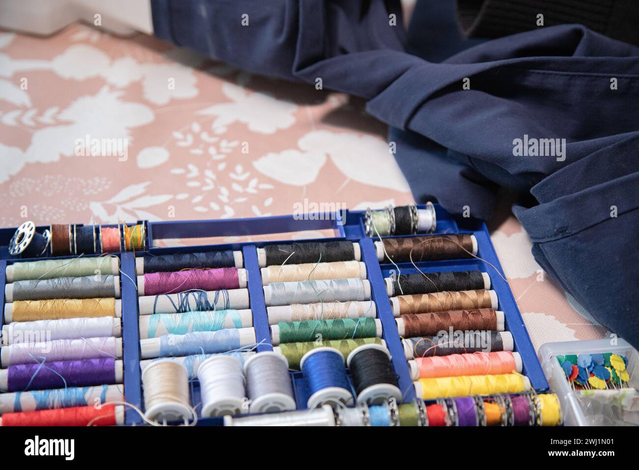 Rolls of thread, spools of thread in different colors for sewing work. Work table with different sewing utensils. Stock Photo