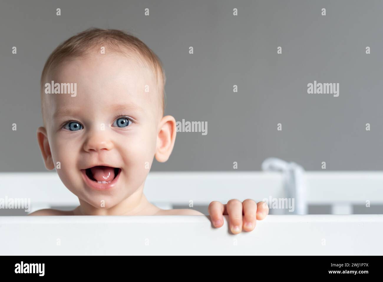 One year old baby standing in a crib smiling Stock Photo - Alamy