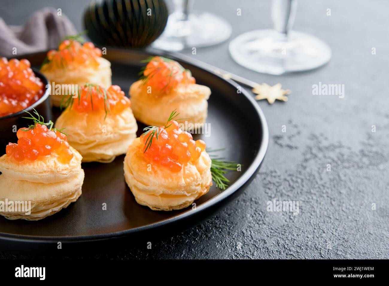 Salmon red caviar toast. Christmas canape or toast with red caviar on black plate on dark background. Idea to xmas snack. Gourmet food. Texture of cav Stock Photo