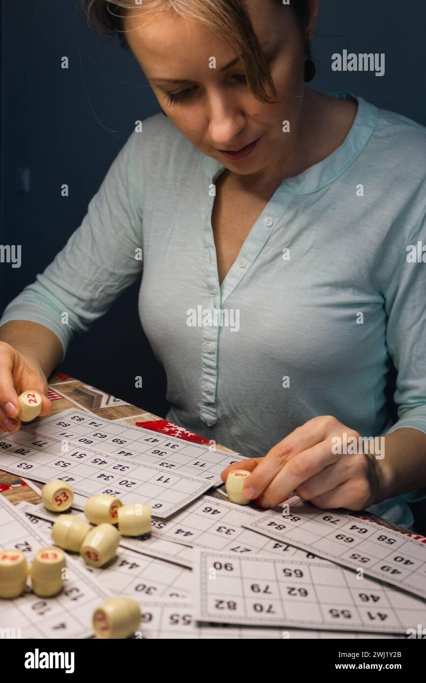 Girl playing in lotto with barrel in hand. Nostalgia lifestyle. Smiling woman playing bingo. Leisure activity. Retro table games. Luck concept. Stock Photo