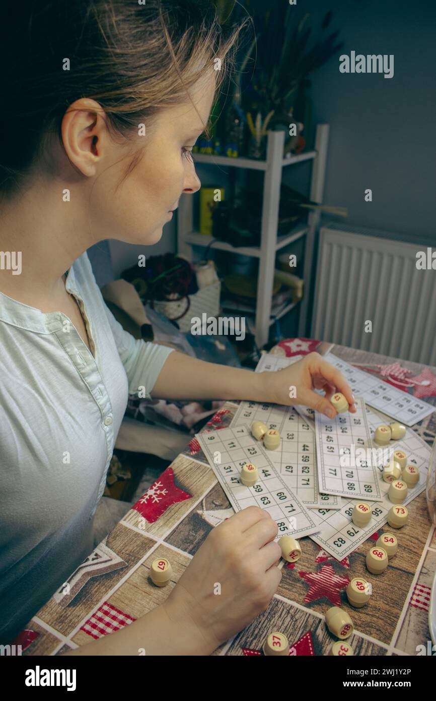 Girl playing in lotto with barrel in hand. Nostalgia lifestyle. Smiling woman playing bingo. Leisure activity. Retro table games. Luck concept. Stock Photo