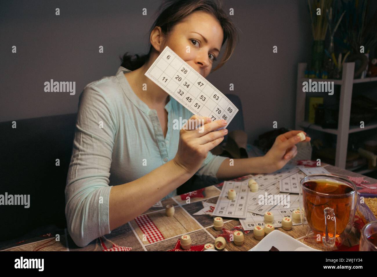 Girl playing in lotto. Nostalgia lifestyle. Woman playing bingo and holding card. Win concept. Leisure activity. Retro table games. Luck concept. Stock Photo