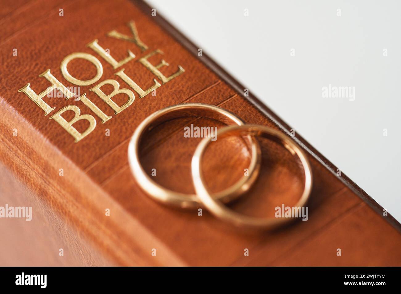Two golden wedding rings and a holy bible represents the concept of marriage and the love between two Christians Stock Photo
