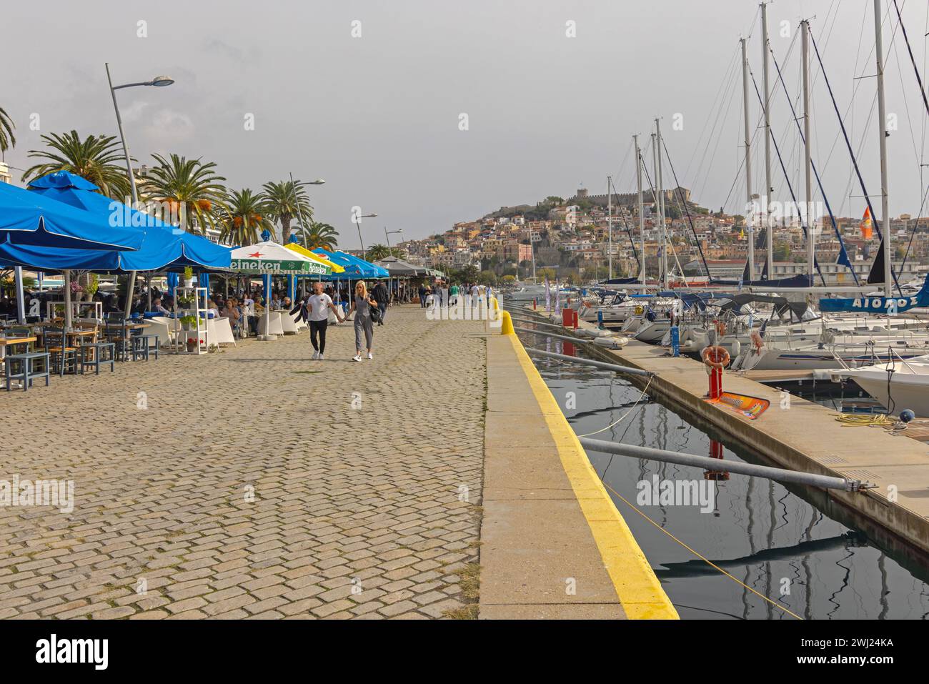 Kavala, Greece - October 22, 2023: People Walking at Promenade Marina Port Harbour Autumn Sunday. Stock Photo