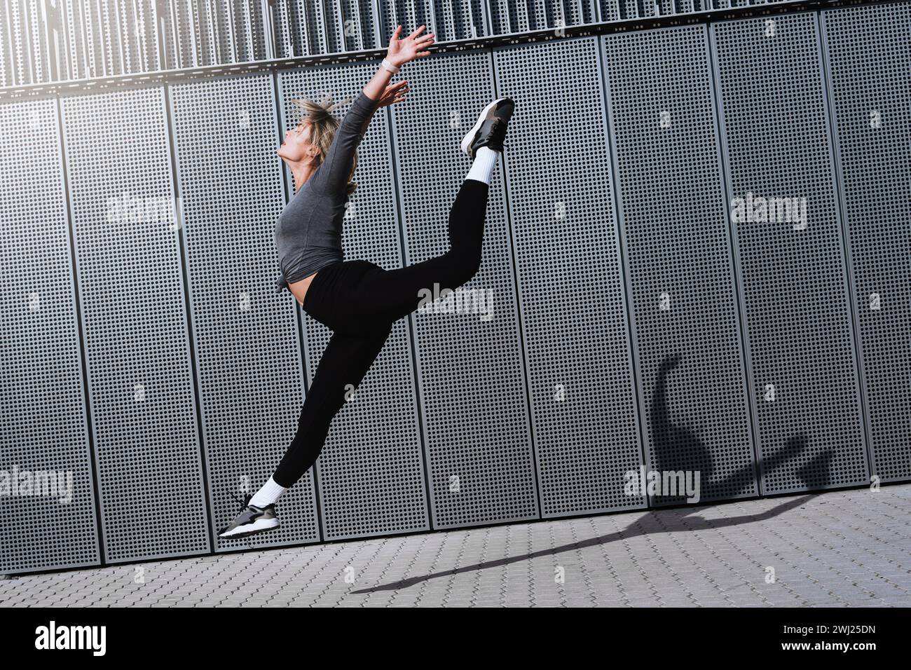 Woman dancer wearing female sportswear performing against  background with modern steel panels Stock Photo