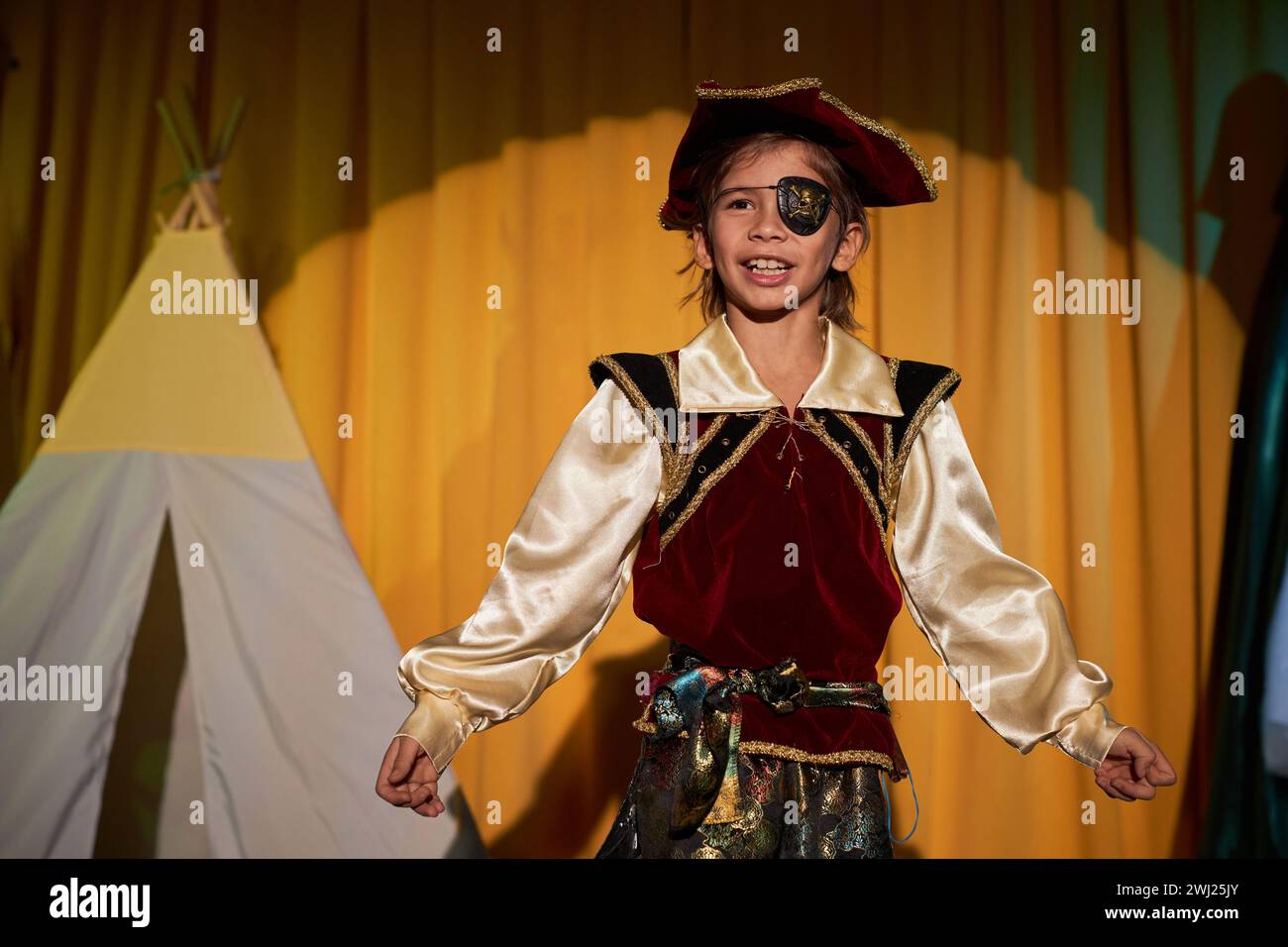 Waist up portrait of young boy wearing pirate costume performing on stage in school play Stock Photo