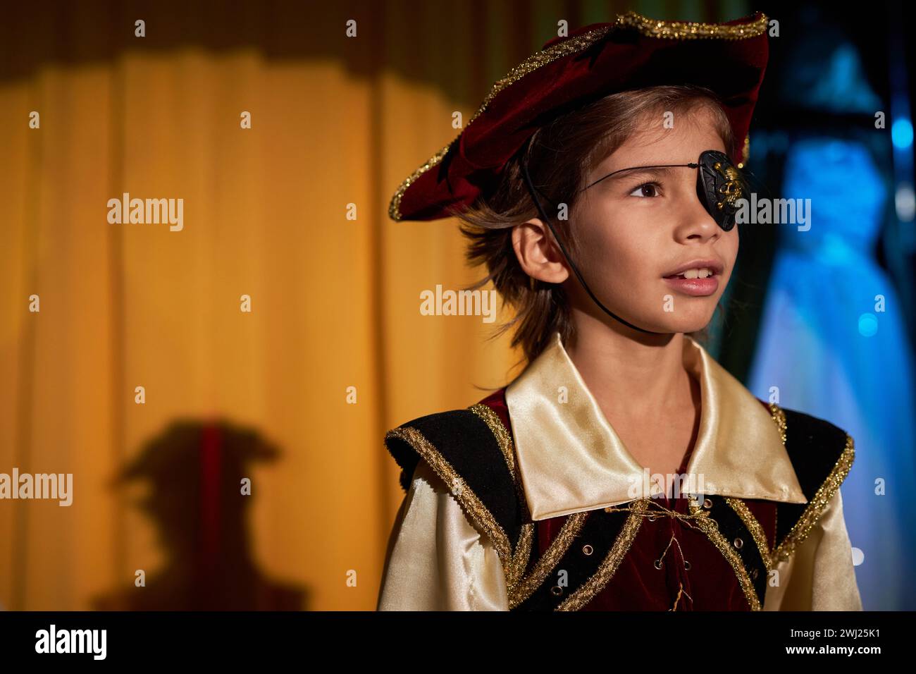 Portrait of young boy wearing pirate costume performing on stage in spotlight, copy space Stock Photo