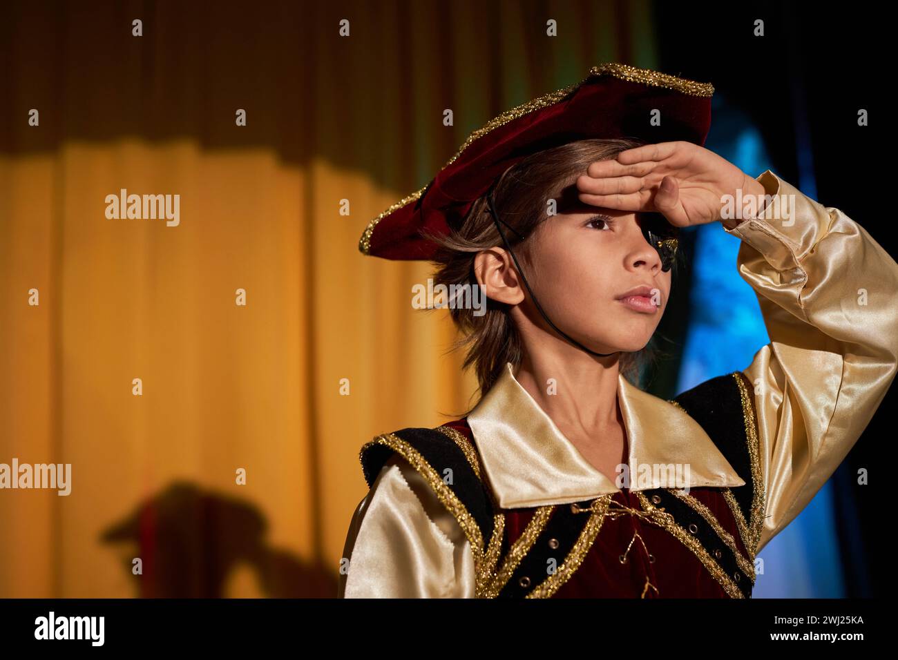 Waist up portrait of boy wearing pirate costume performing on stage in spotlight and talking to audience, copy space Stock Photo