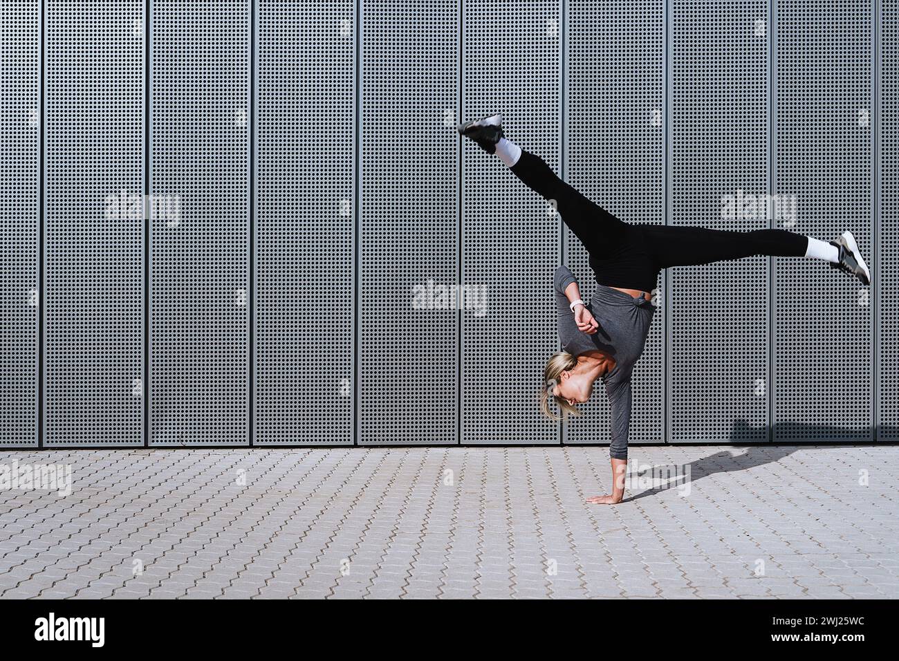 Woman athlete wearing female sportswear doing cartwheel movement on the street Stock Photo