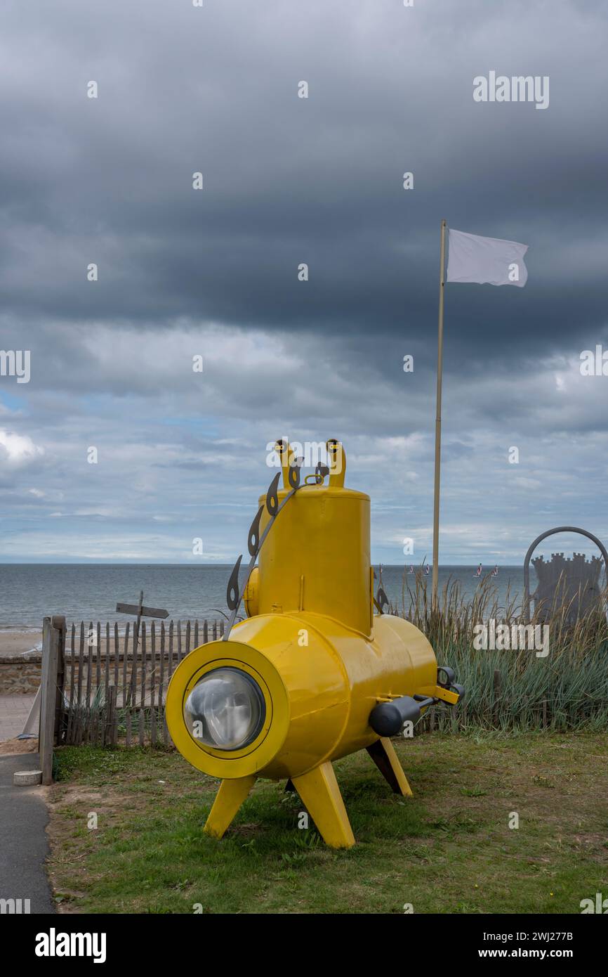 A yellow submarine, a white flag, the beach and the sea with a cloudy sky Stock Photo