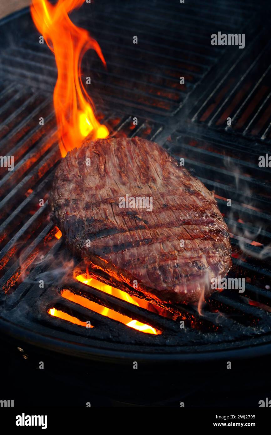 Traditional American barbecue flanksteak steak as closeup on a charcoal grill with fire Stock