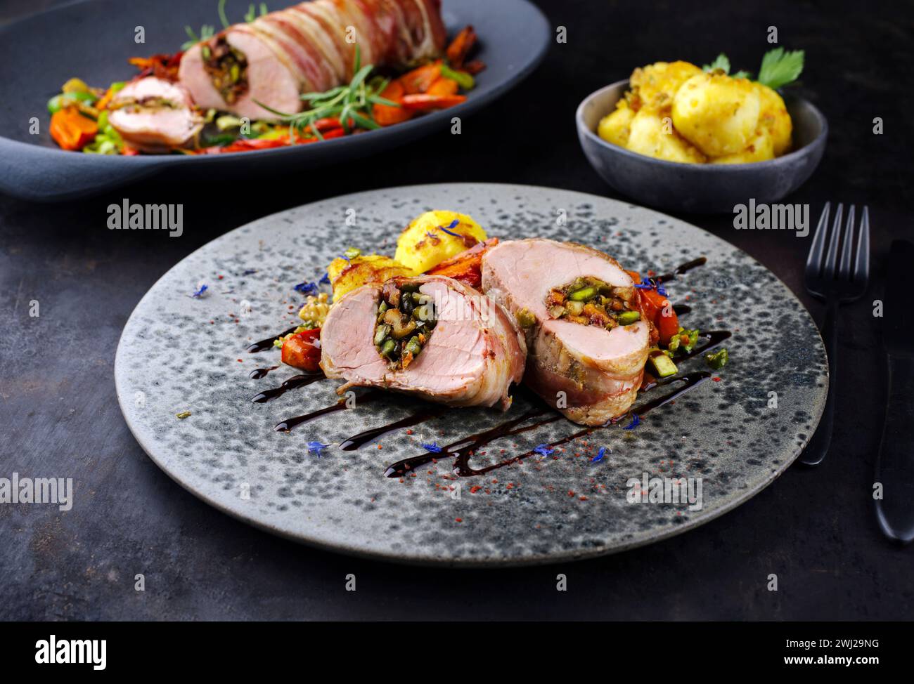 Roasted Mangalica pork tenderloin stuffed with chopped walnuts and pumpkin wrapped in bacon and served with vegetables as close- Stock Photo