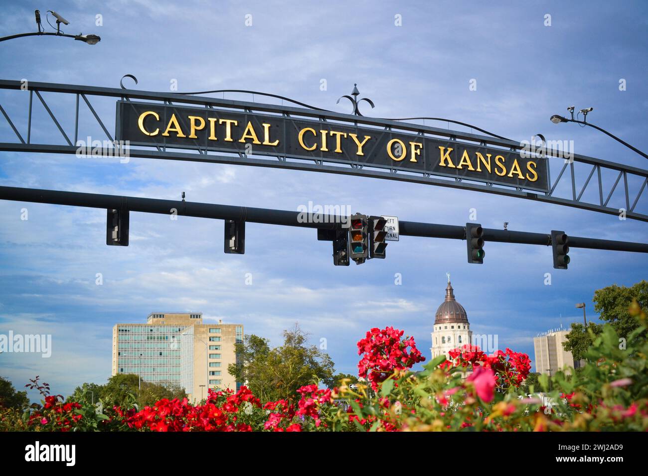 Capital City of Kansas Arch Signage Over Capitol Dome and Flowers Stock Photo