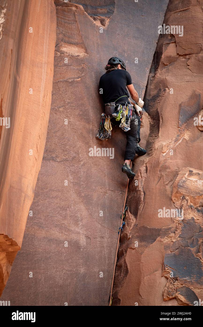 Rear view of man climbing rocky cliff at desert Stock Photo