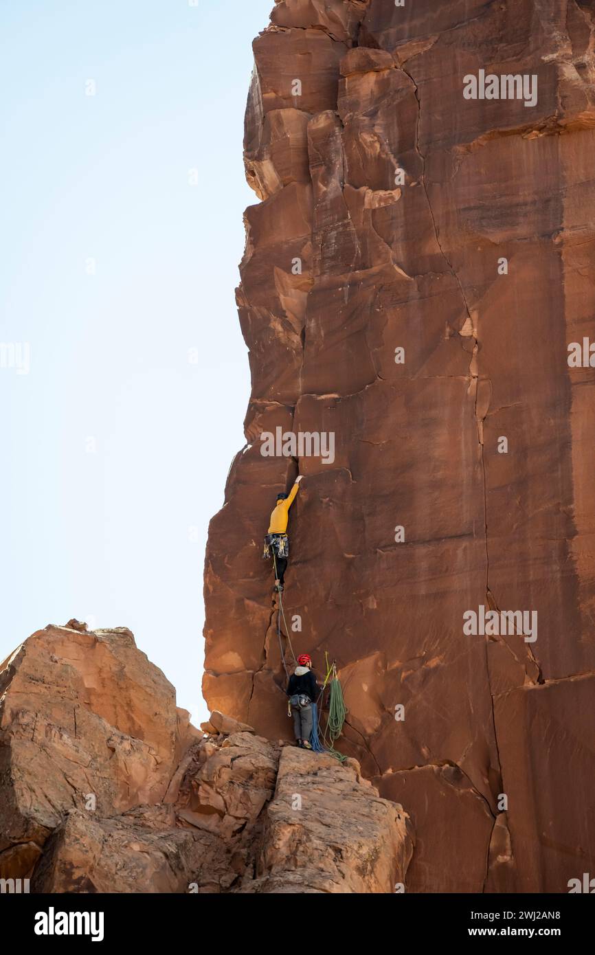 Male mountaineers climbing rocky cliff against sky Stock Photo