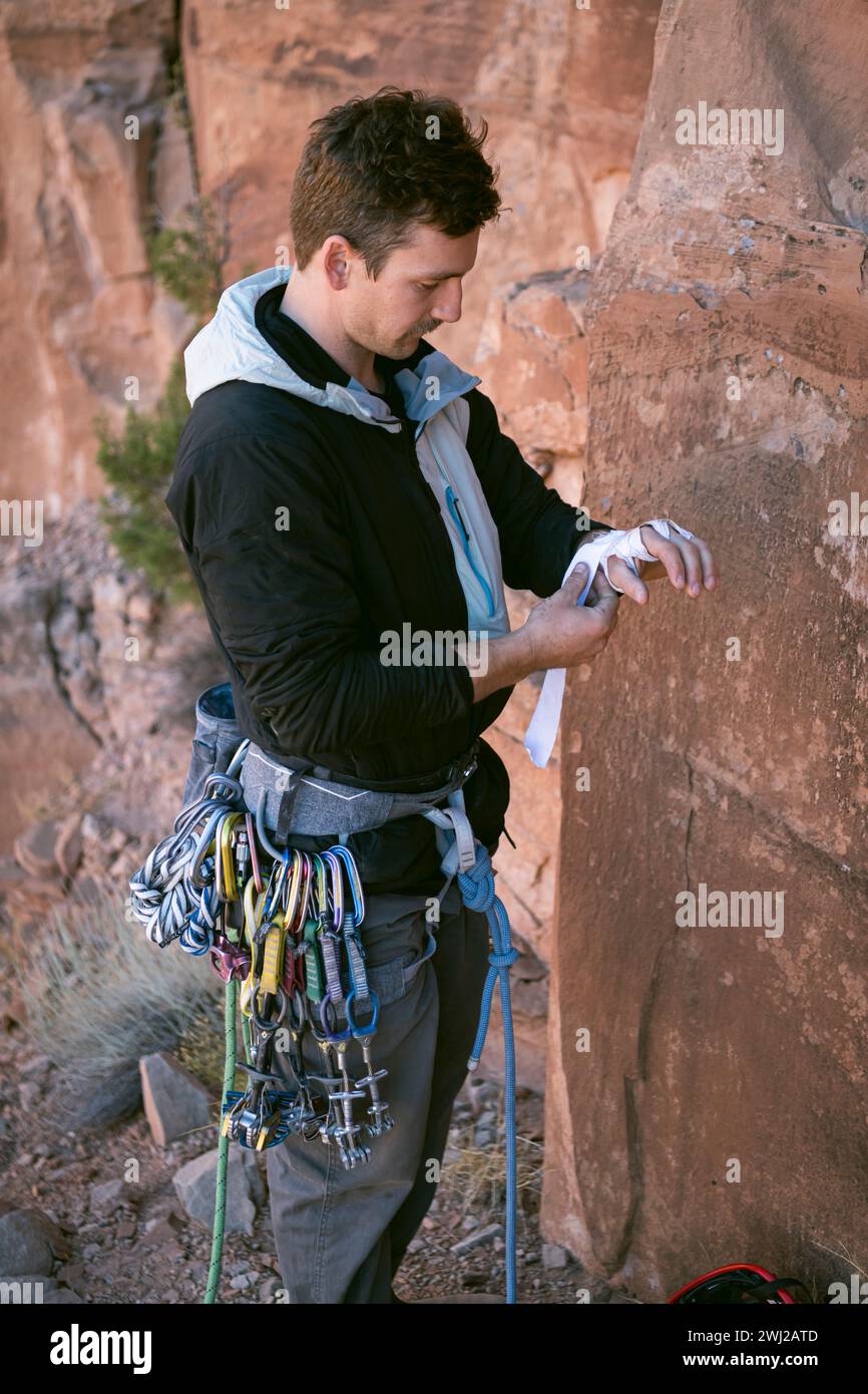 Male mountaineer wearing tape gloves by cliff at desert Stock Photo