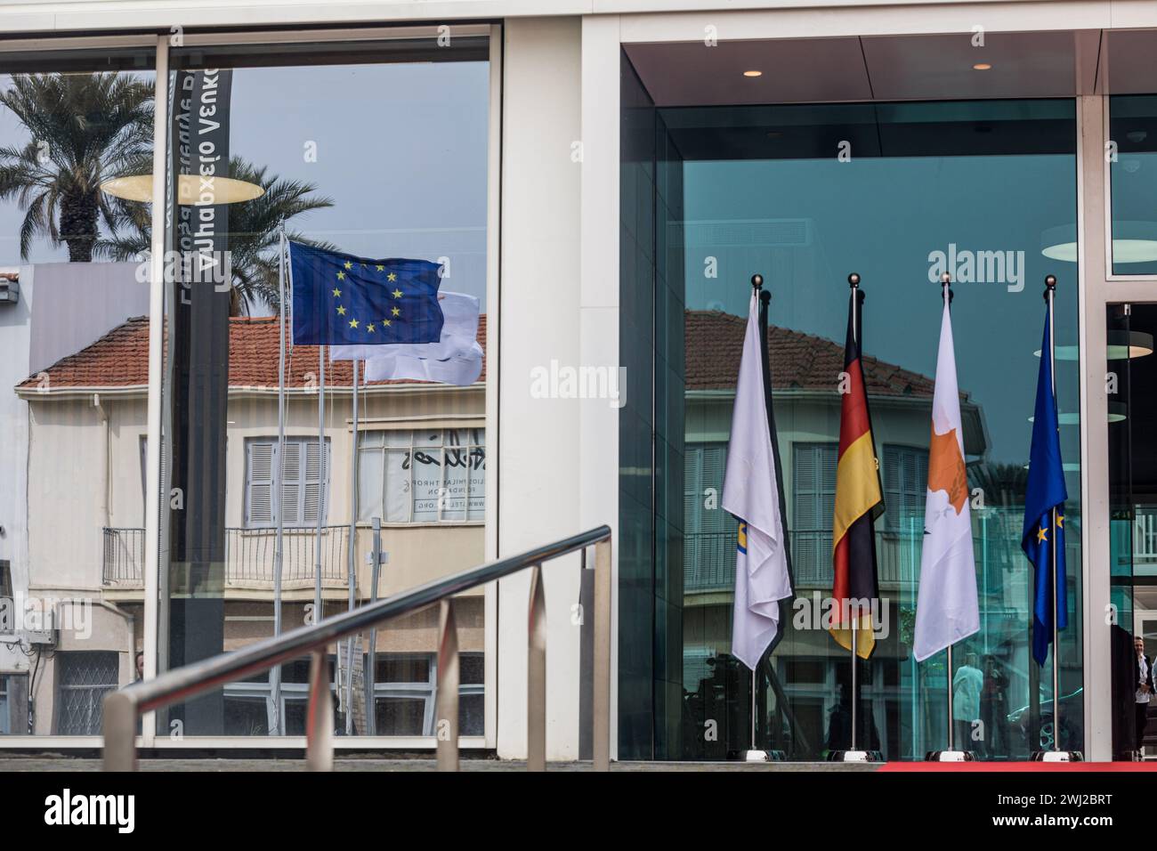 Nicosia, Nicosia, Cyprus. 12th Feb, 2024. The flags of Cyprus, Germany, EU and Nicosia municipality are seen outside the Town Hall, Nicosia, Cyprus, on Feb. 12, 2024. The President of Germany, Frank-Walter Steinmeier is being guided from President of Cyprus, Nikos Christodoulides and Nicosia Mayor, Constantinos Yiorkadjis to the old city of Nicosia, where the barricades that separate the Greek and Turkish side of the city are visible, also called the ''Green Line''. Nicosia is the last divided European capital. The visit of the German President is the first ever since the establishment of R Stock Photo