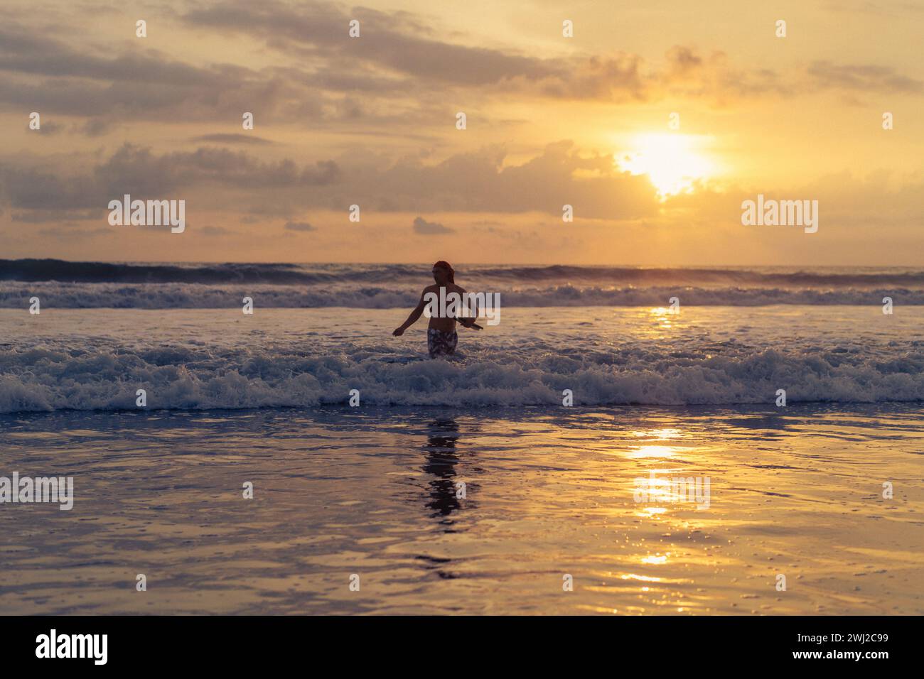 Fisherman catches fish with a net in the ocean at sunset, Bali. Stock Photo