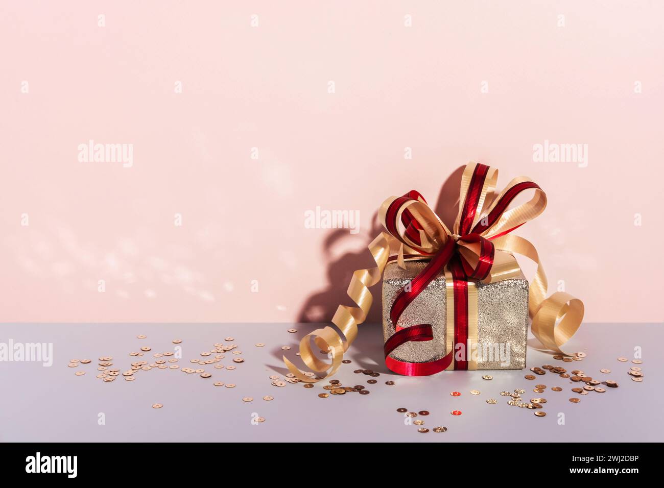Festively wrapped gift box. Golden paper with ribbon and bow. Holiday Shopping concept Stock Photo