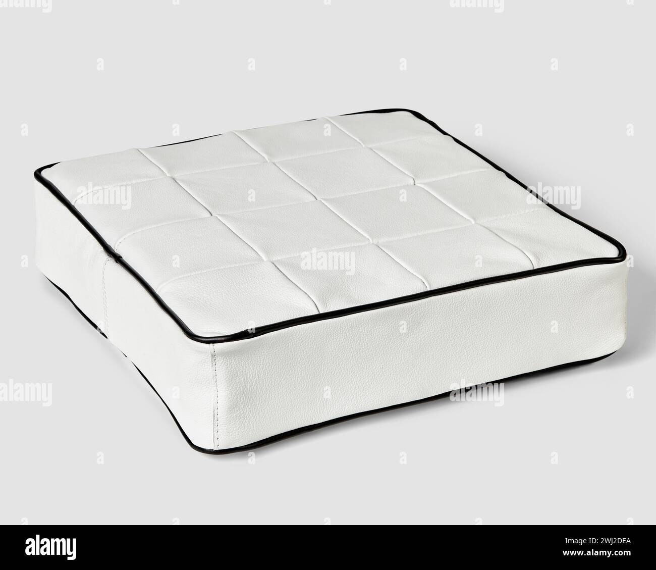 Square cushion in white patchwork leather with contrasting black trim Stock Photo