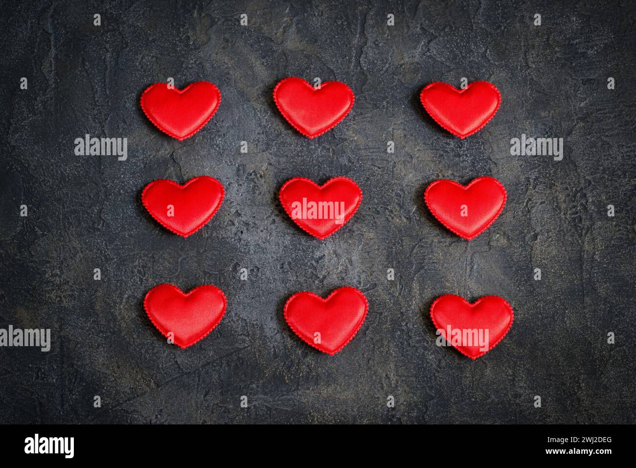 Satin red hearts on a dark background. Valentine's Day card. Stock Photo