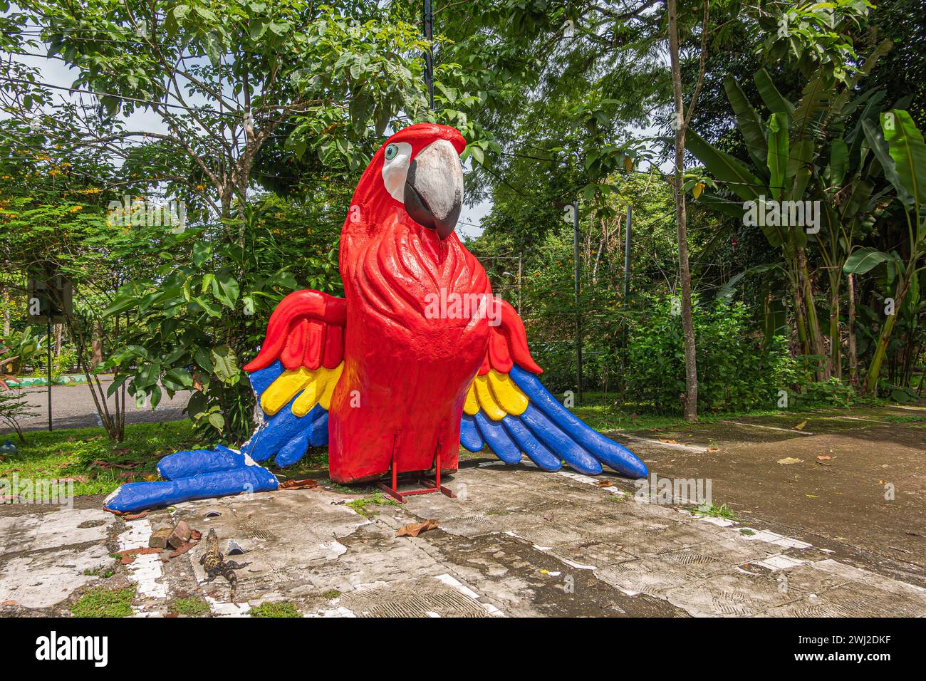 Costa Rica, Parque Nacional Carara - July 22, 2023: At entrance, giant bright colored statue of Scarlet Macaw. Green foliage backdrop Stock Photo