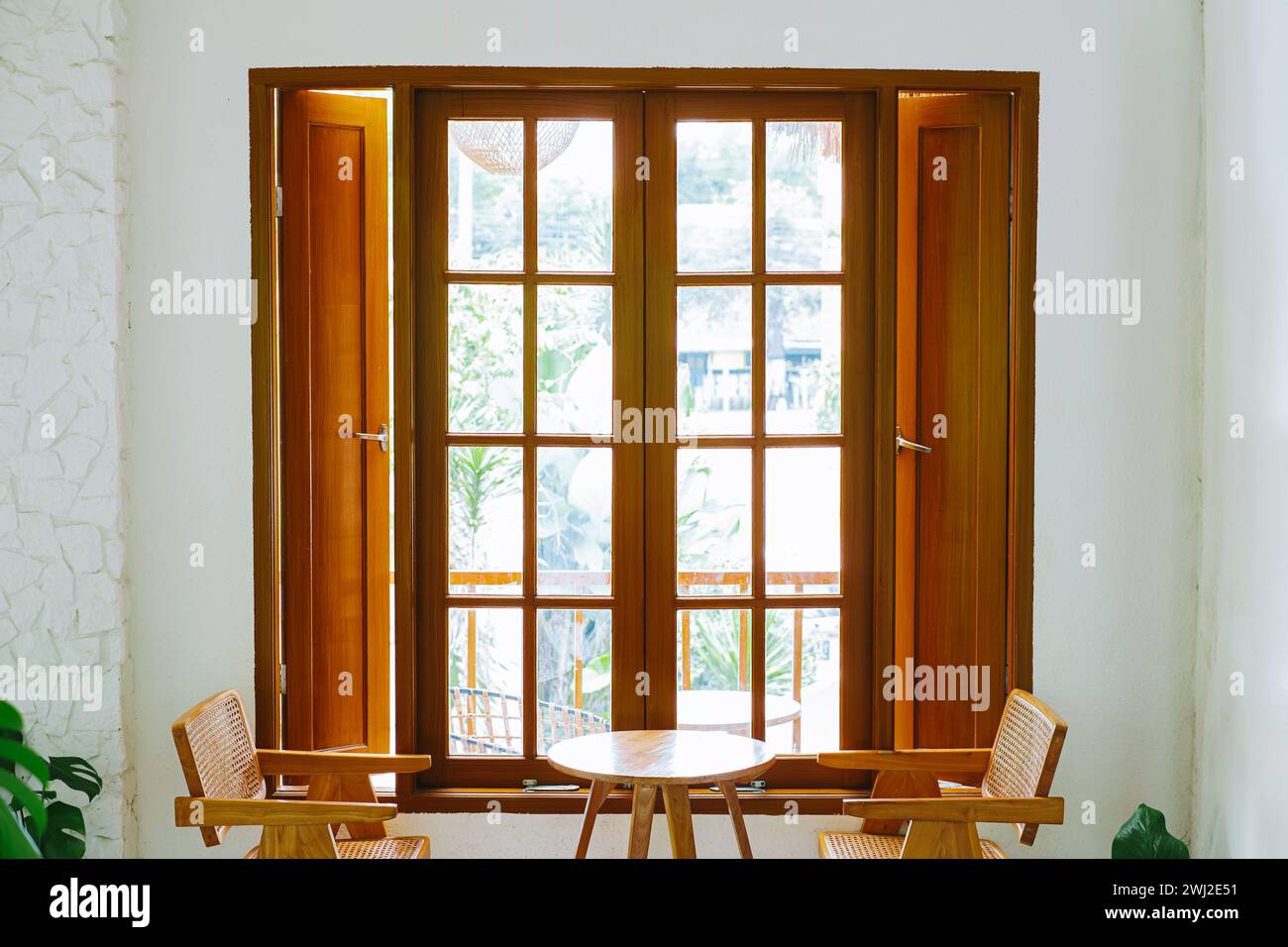Indoor table setting with a large wooden window. Tropical interior concept. Stock Photo