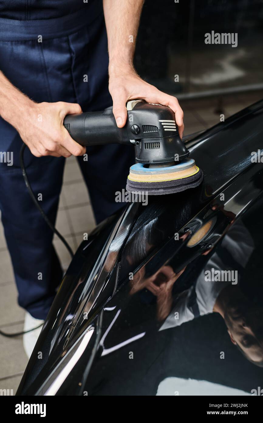 cropped view of dedicated professional worker using polishing machine carefully on black car Stock Photo